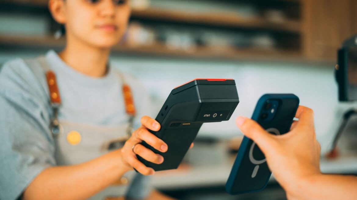 Caissier effectuant un paiement sans contact avec smartphone et terminal, comparaison casino