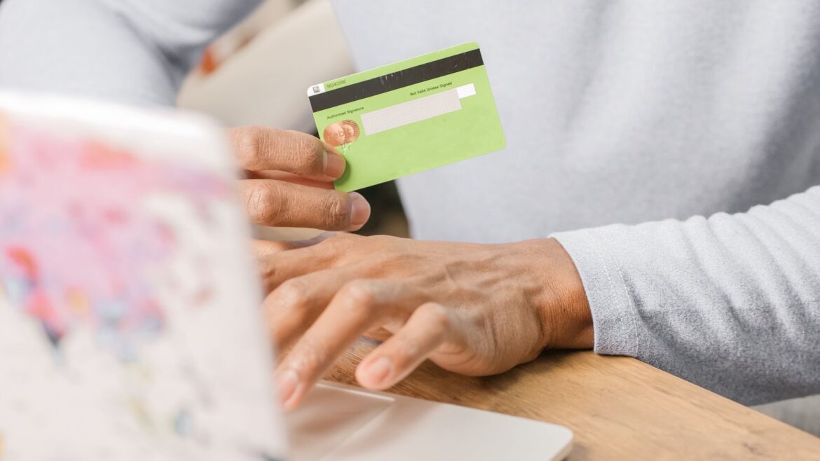 Mains tenant une carte verte devant un ordinateur portable pour paiement casino