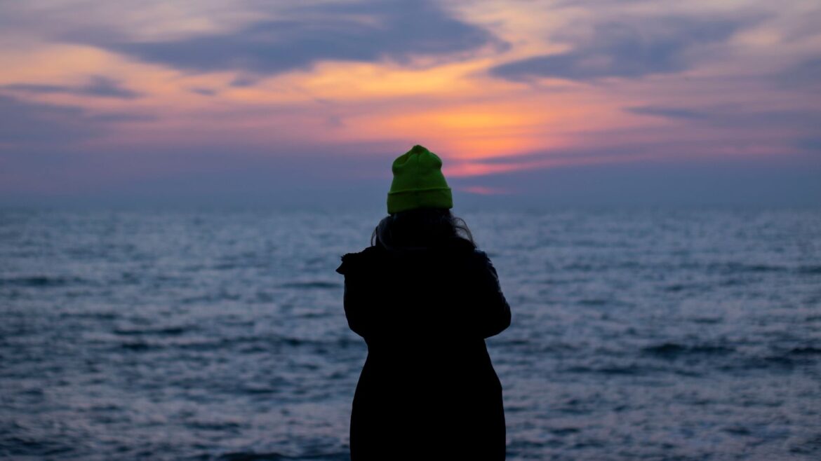 Personne debout sur la plage face au coucher de soleil, jouer avec mesure