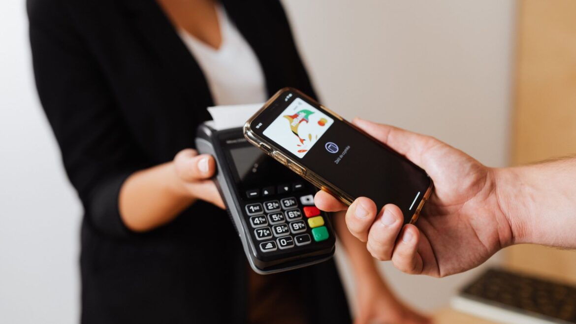 Personne effectuant un paiement sans contact avec smartphone au comptoir d'un magasin