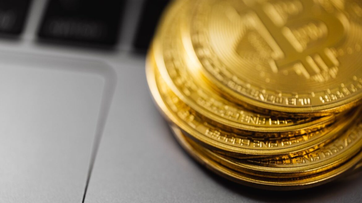 Pile de pièces Bitcoin dorées posée sur un clavier d'ordinateur portable
