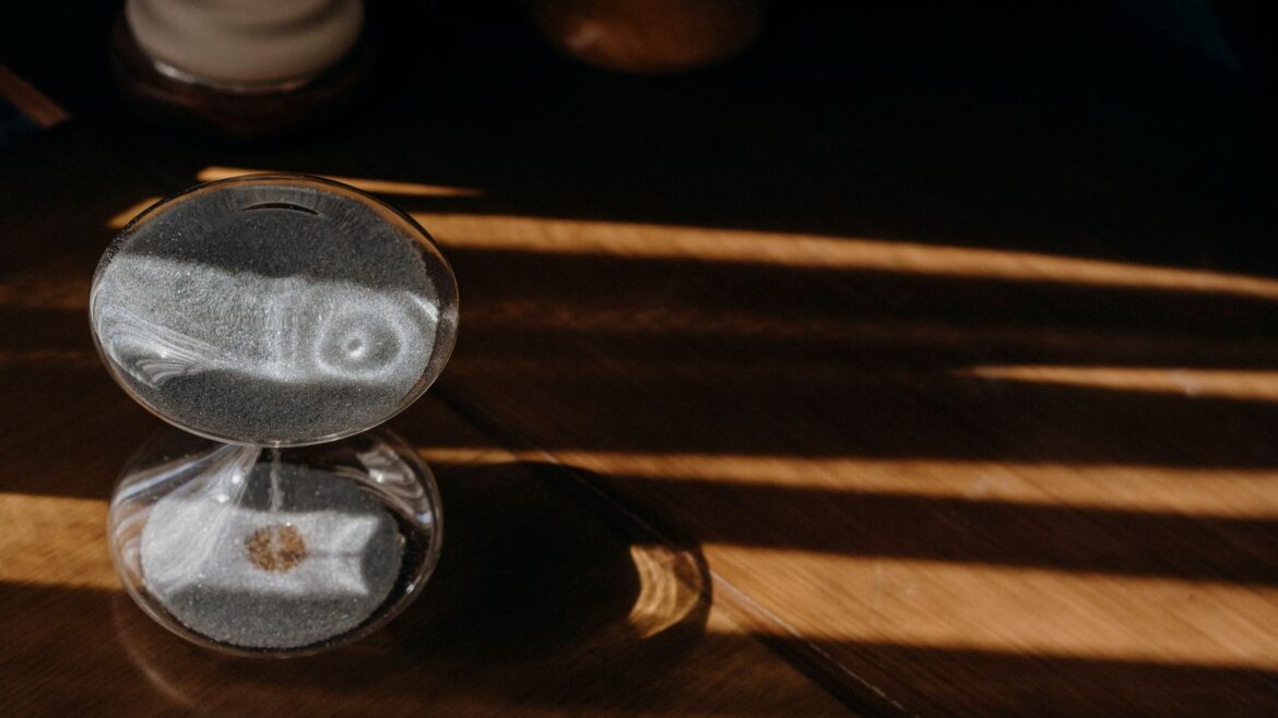 Sablier en bois projetant une ombre sur une table, lumière matinale, gestion du temps de jeu
